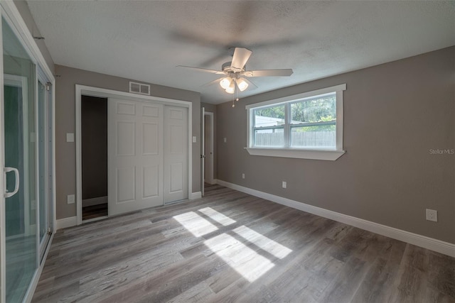 unfurnished bedroom with hardwood / wood-style flooring, a closet, and a textured ceiling