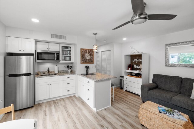 kitchen featuring ceiling fan, stainless steel appliances, white cabinets, light wood-type flooring, and light stone countertops