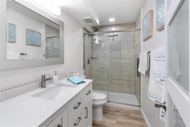 bathroom with wood-type flooring, toilet, vanity, and an enclosed shower