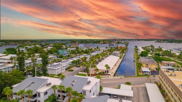 aerial view at dusk featuring a residential view and a water view