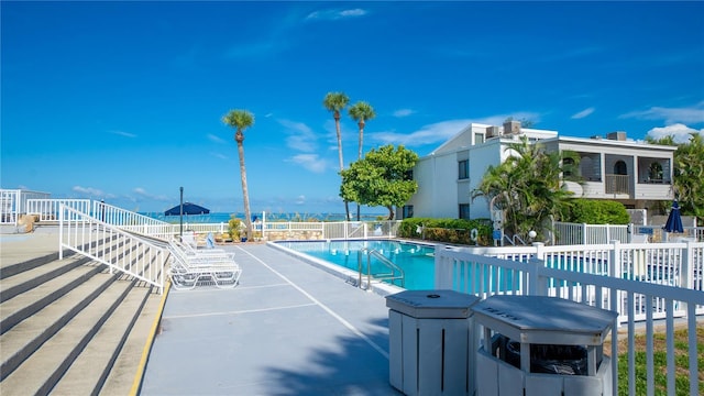 community pool with a patio area and fence