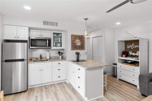 kitchen featuring light wood-type flooring, kitchen peninsula, white cabinets, stainless steel appliances, and sink