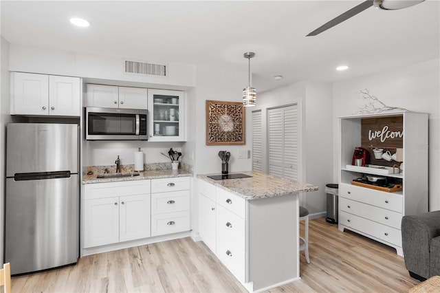 kitchen featuring visible vents, appliances with stainless steel finishes, white cabinetry, a sink, and a peninsula