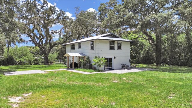 view of front of house with a front yard, a patio, and central air condition unit