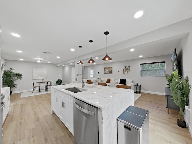 kitchen featuring light wood-type flooring, stainless steel dishwasher, a kitchen island with sink, sink, and white cabinets