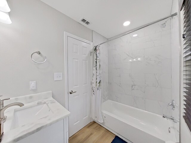 bathroom featuring hardwood / wood-style floors, vanity, and shower / bath combo