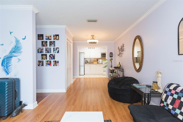 foyer entrance with crown molding, a textured ceiling, and light hardwood / wood-style floors