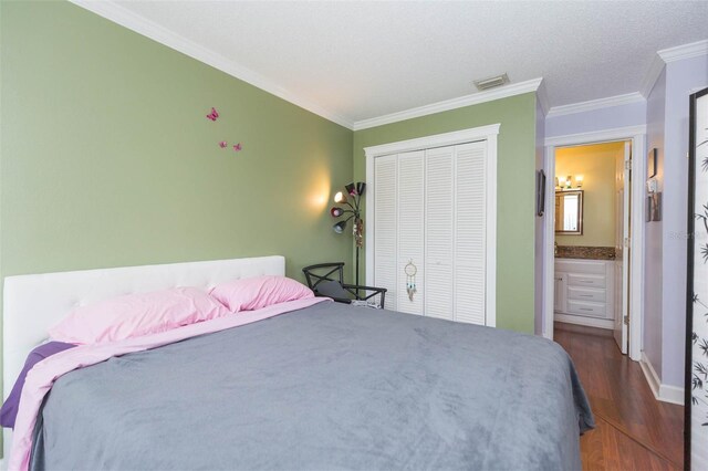 bedroom with wood-type flooring, crown molding, a closet, and ensuite bathroom