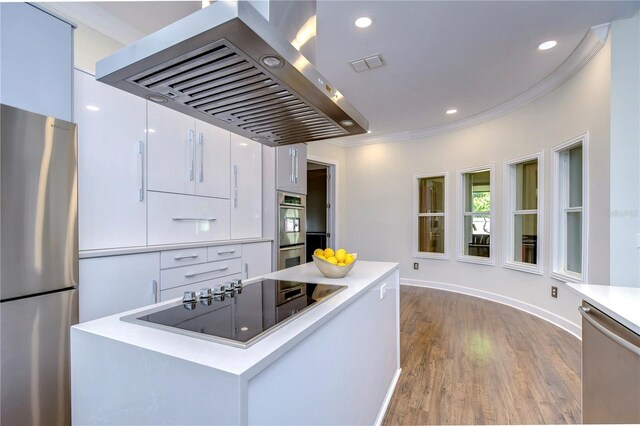 kitchen featuring crown molding, light hardwood / wood-style flooring, white cabinets, appliances with stainless steel finishes, and island range hood