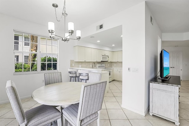 dining room with a notable chandelier, sink, and light tile patterned flooring