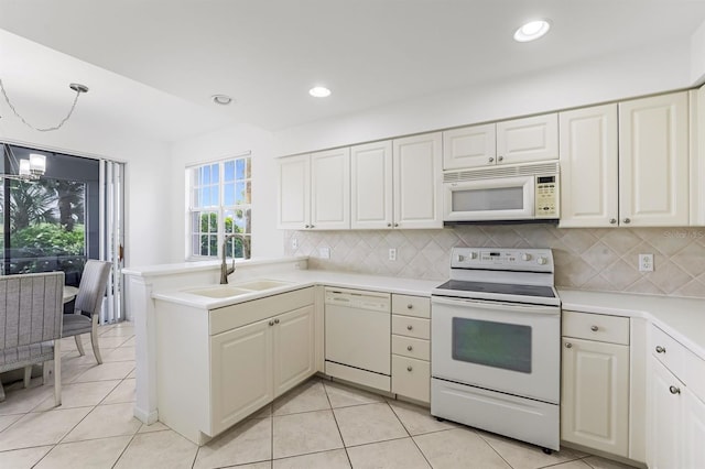 kitchen featuring sink, light tile patterned floors, kitchen peninsula, pendant lighting, and white appliances