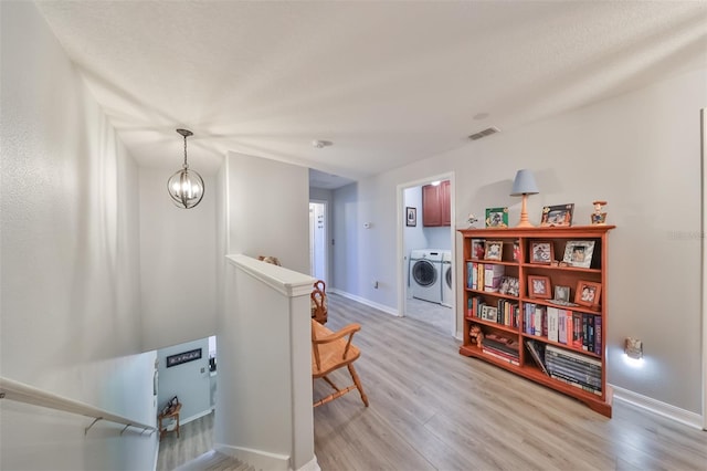 living area with a notable chandelier, separate washer and dryer, and light hardwood / wood-style flooring