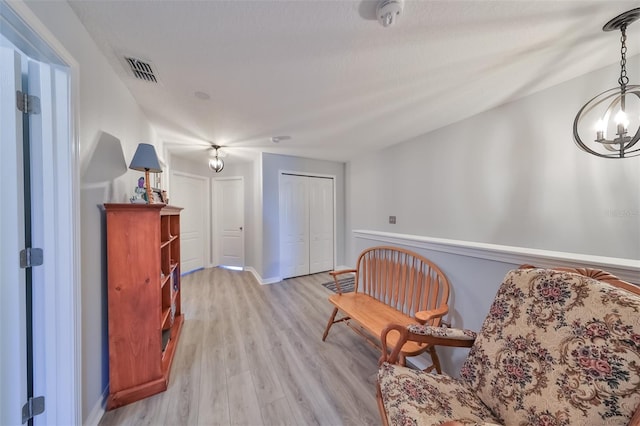 sitting room with hardwood / wood-style floors and an inviting chandelier