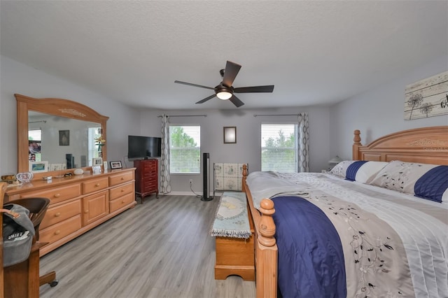 bedroom featuring light wood-type flooring, a textured ceiling, and ceiling fan