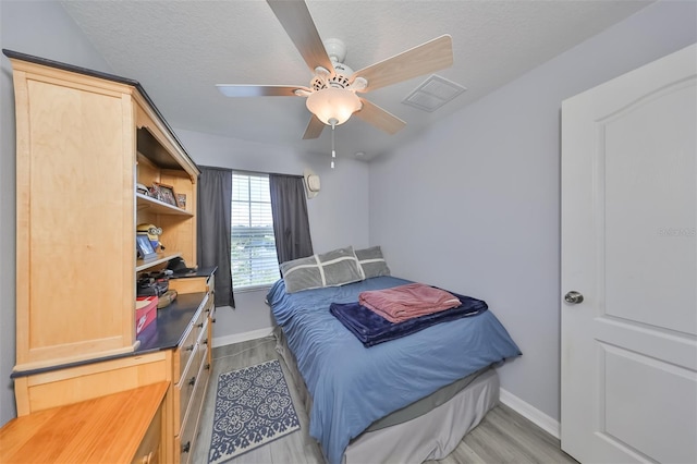 bedroom featuring light wood-type flooring, a textured ceiling, and ceiling fan