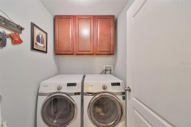 clothes washing area with cabinets, a textured ceiling, and washer and dryer