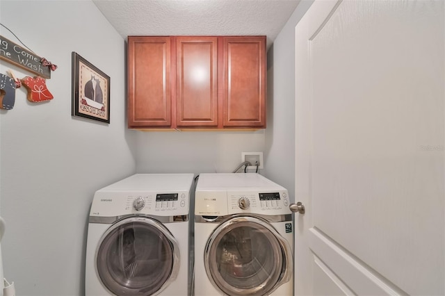 washroom featuring cabinets, washing machine and clothes dryer, and a textured ceiling