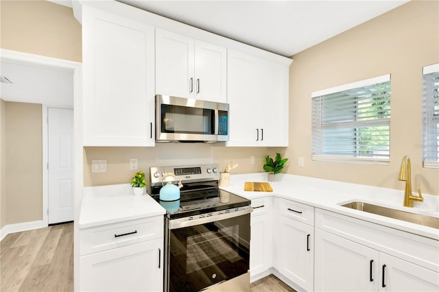 kitchen with white cabinets, stainless steel appliances, light hardwood / wood-style floors, and sink