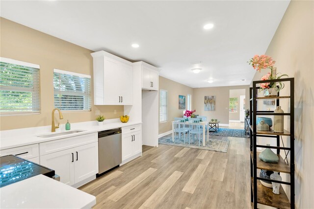 kitchen featuring stove, white cabinets, sink, light wood-type flooring, and dishwasher