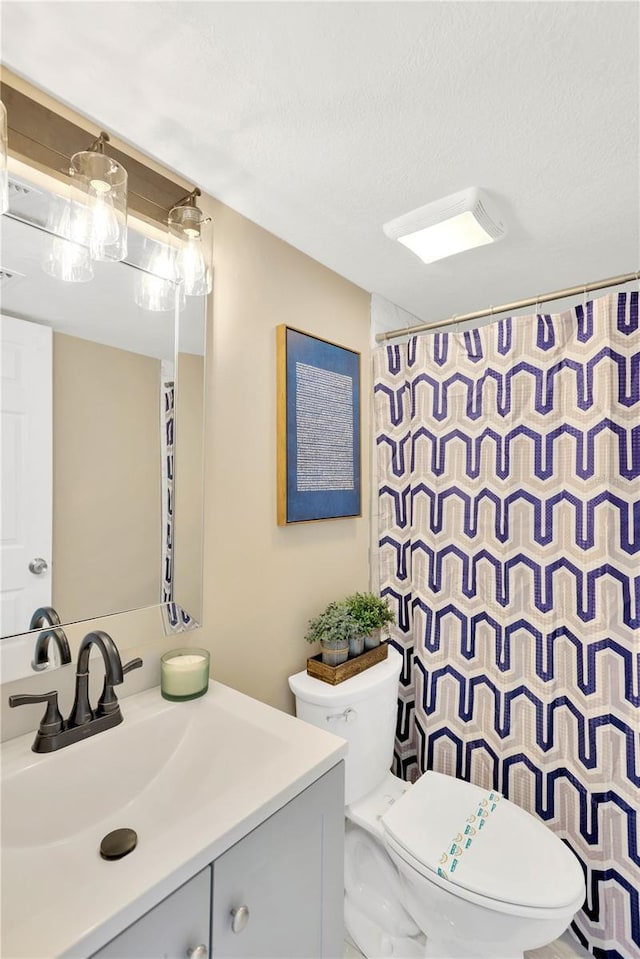 bathroom with vanity, a textured ceiling, and toilet