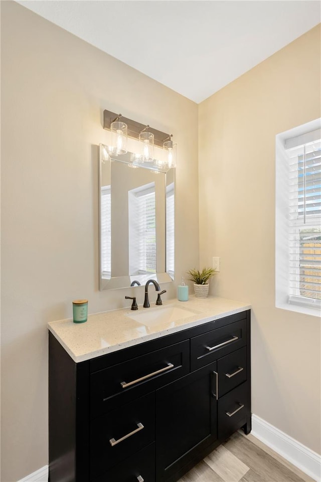 bathroom with vanity, hardwood / wood-style flooring, and a healthy amount of sunlight