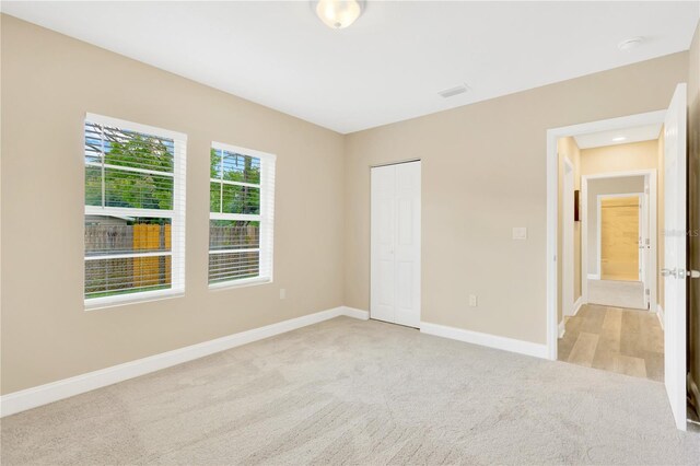 unfurnished bedroom featuring light carpet and a closet