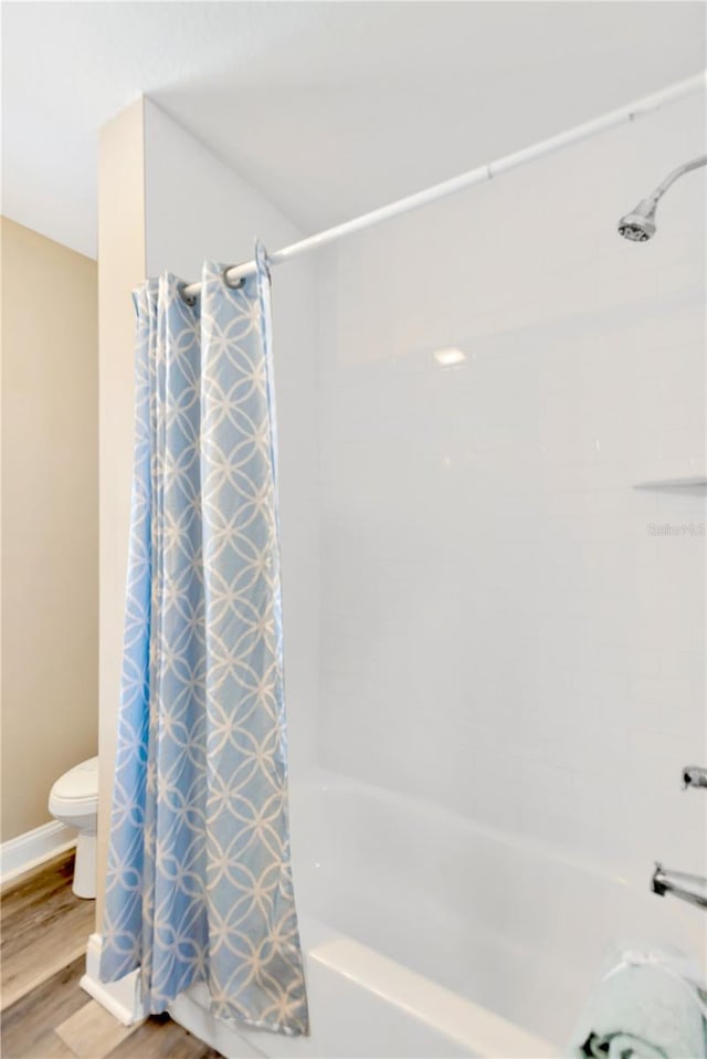 bathroom featuring shower / tub combo with curtain, toilet, and wood-type flooring