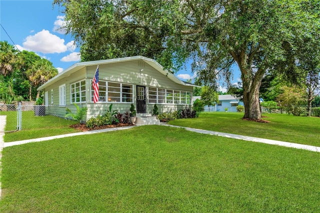 view of front of home with a sunroom and a front yard