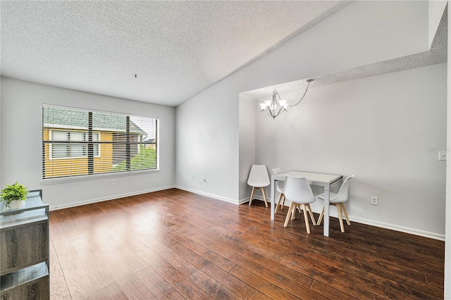 dining area featuring an inviting chandelier, a textured ceiling, wood-type flooring, and vaulted ceiling