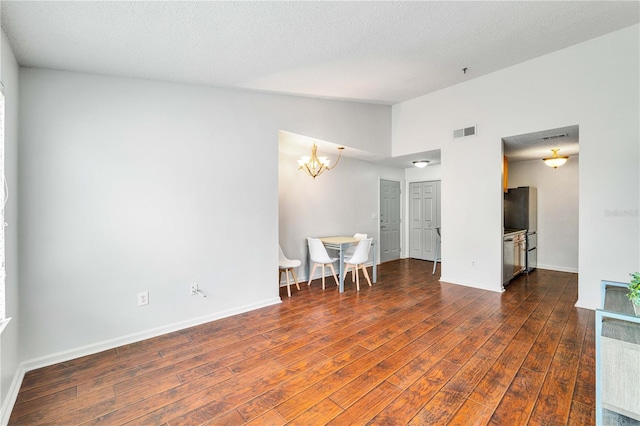 spare room featuring baseboards, visible vents, dark wood finished floors, an inviting chandelier, and vaulted ceiling