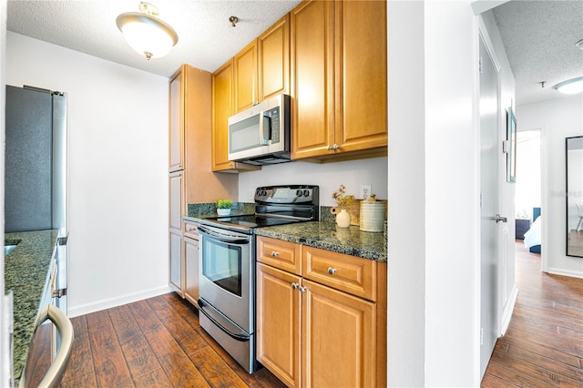 kitchen with dark wood finished floors, baseboards, appliances with stainless steel finishes, and a textured ceiling