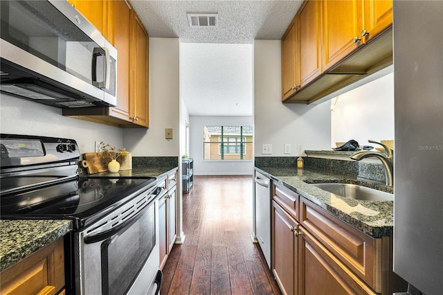 kitchen featuring visible vents, dark wood-type flooring, stainless steel appliances, a textured ceiling, and a sink