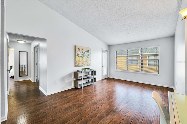 empty room with a textured ceiling, baseboards, lofted ceiling, and wood-type flooring