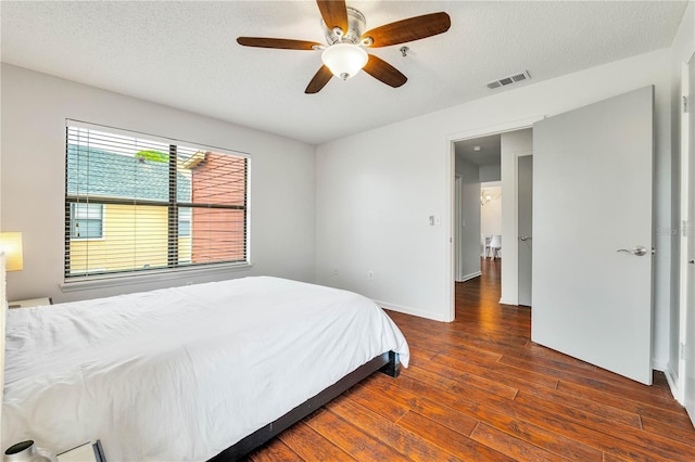 bedroom featuring visible vents, a textured ceiling, a ceiling fan, and hardwood / wood-style flooring