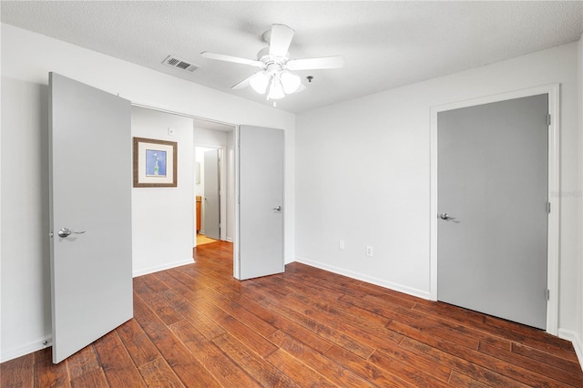 spare room featuring baseboards, visible vents, ceiling fan, hardwood / wood-style flooring, and a textured ceiling