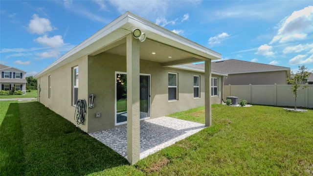 rear view of house featuring central air condition unit and a yard