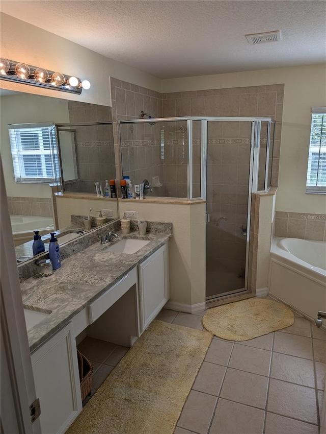 bathroom featuring tile patterned flooring, shower with separate bathtub, vanity, and a textured ceiling