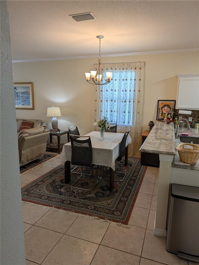 tiled dining area with a notable chandelier, sink, a textured ceiling, and ornamental molding