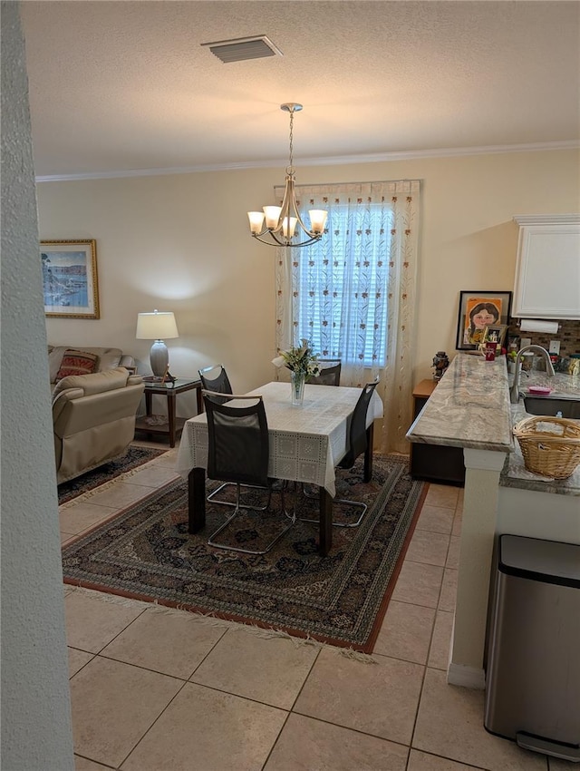dining space featuring light tile patterned flooring, sink, ornamental molding, a notable chandelier, and a textured ceiling