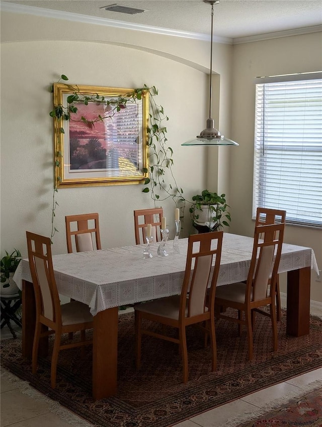 dining space featuring ornamental molding and tile patterned flooring