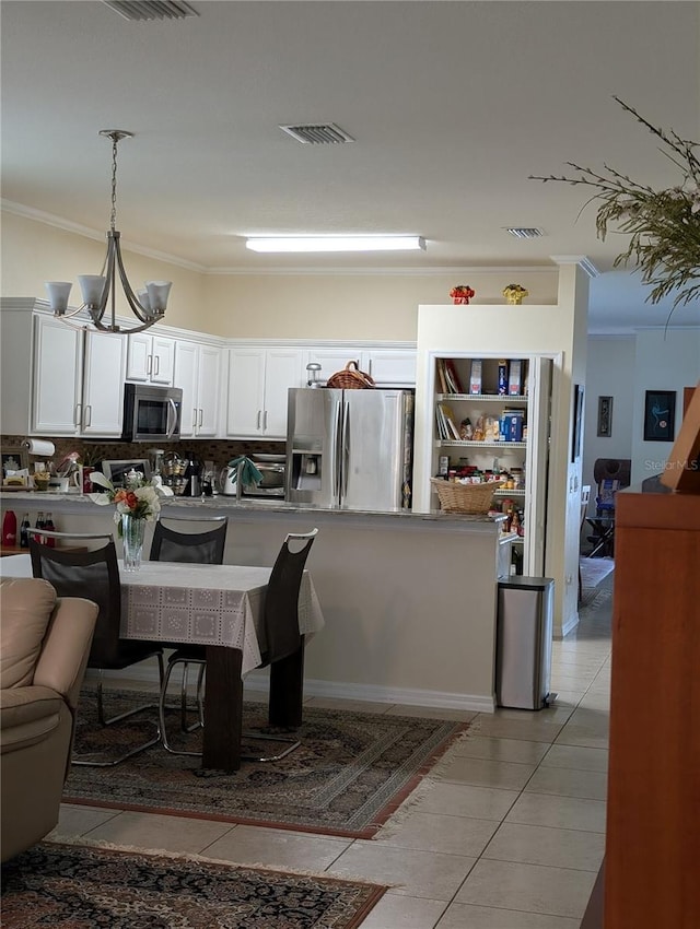 kitchen with light tile patterned flooring, stainless steel appliances, decorative light fixtures, and white cabinets