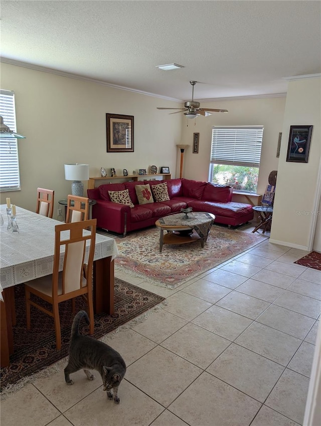 living room featuring crown molding, light tile patterned flooring, ceiling fan, and a textured ceiling