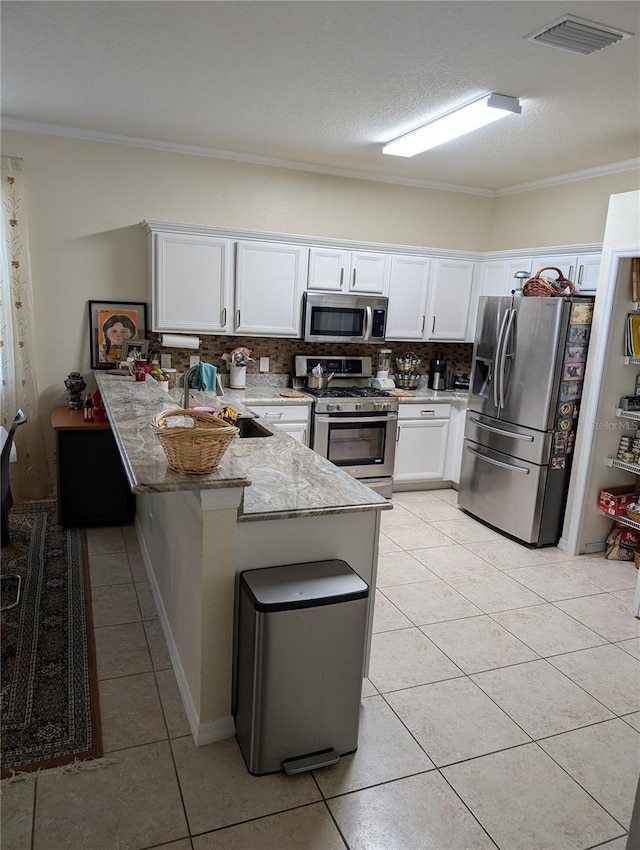 kitchen with appliances with stainless steel finishes, white cabinets, backsplash, kitchen peninsula, and light stone countertops