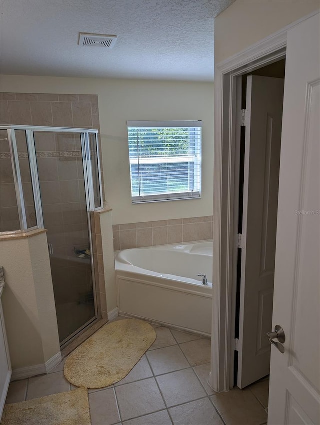 bathroom with tile patterned flooring, plus walk in shower, and a textured ceiling
