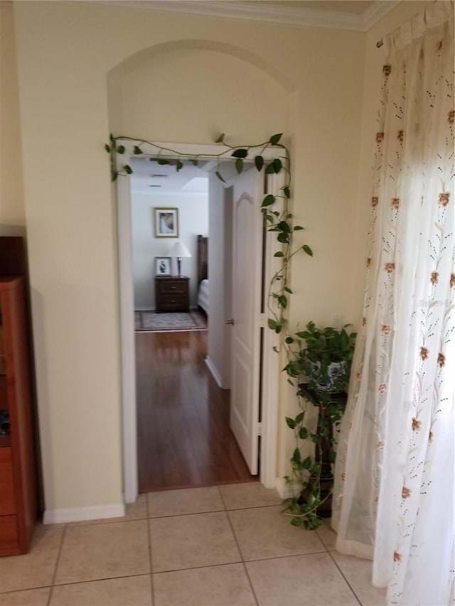hall featuring light tile patterned floors and ornamental molding