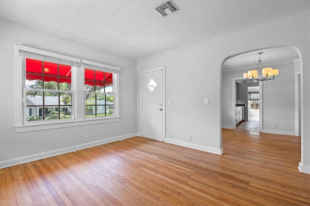 entryway with hardwood / wood-style floors, a textured ceiling, and a notable chandelier