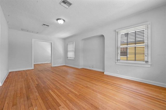 unfurnished room with a textured ceiling and light hardwood / wood-style floors