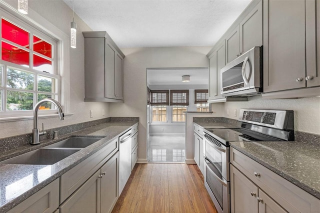 kitchen with sink, appliances with stainless steel finishes, gray cabinetry, a wealth of natural light, and light hardwood / wood-style floors