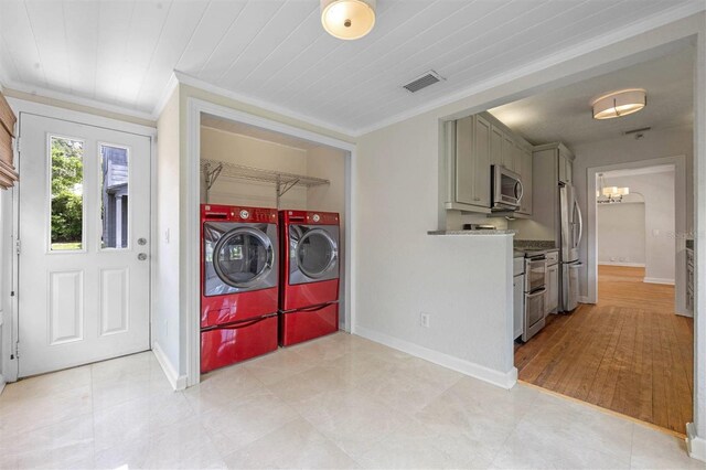 laundry room featuring ornamental molding, washer and clothes dryer, and a notable chandelier