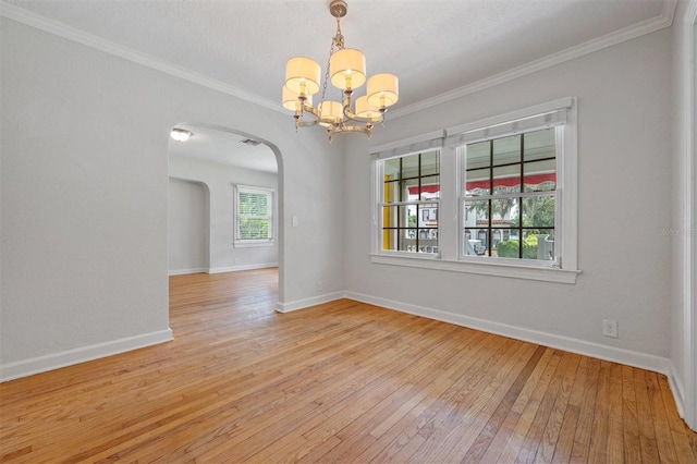 empty room featuring crown molding, a notable chandelier, and light wood-type flooring